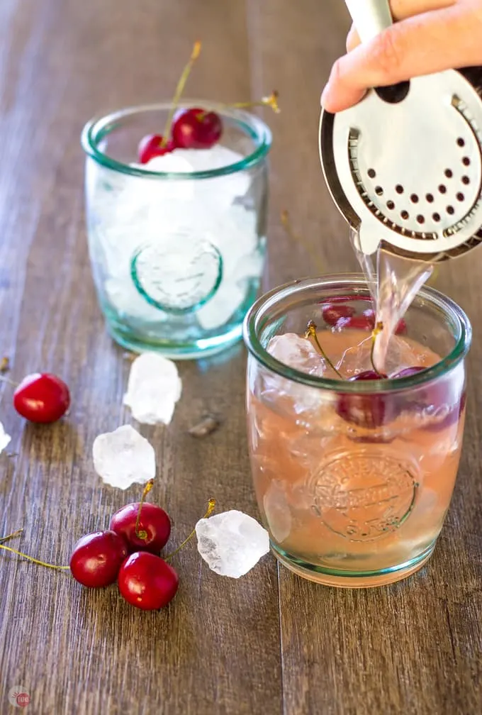 Pouring Cherry Lime Bourbon Smash over ice