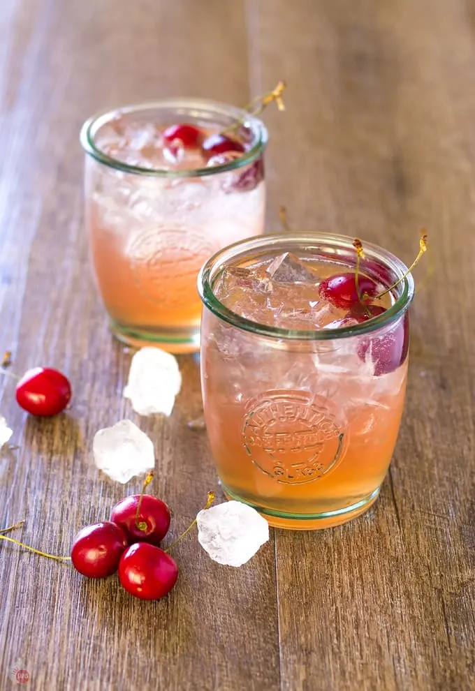 Side angle of two glasses of refreshing Cherry Lime Bourbon Smash 
