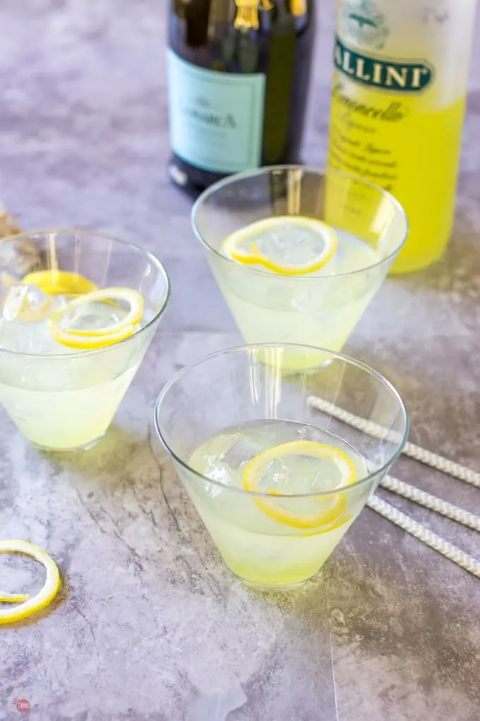 half filled cocktail glasses with straws