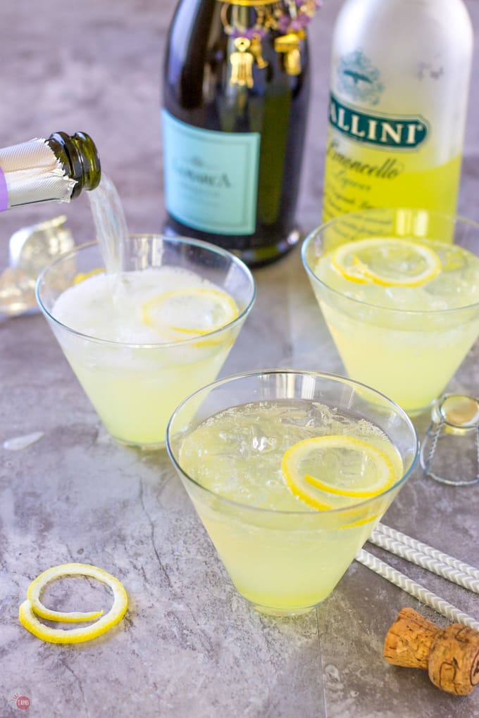 prosecco pouring into a limoncello cocktail glass behind two other glasses