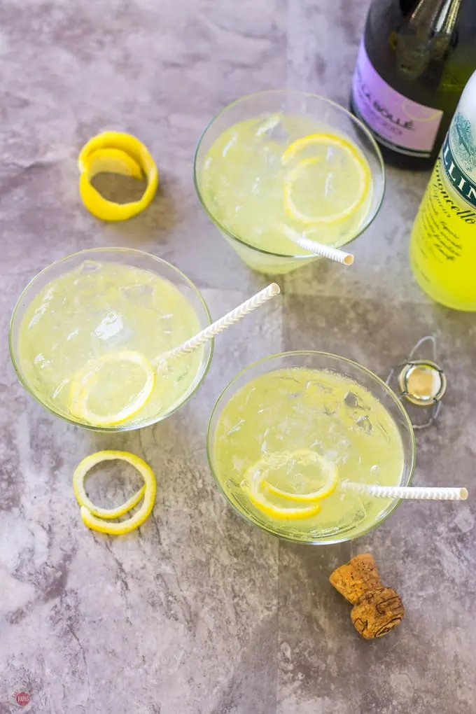 overhead picture of 3 martini glasses with straws and two prosecco bottles