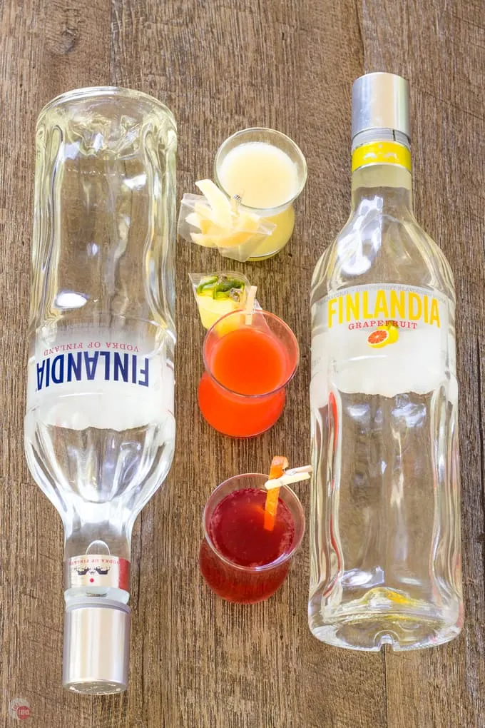 2 bottles of Finlandia and 3 mini cocktails on a wooden surface.