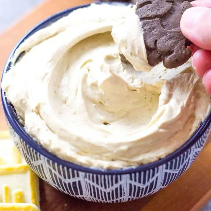Close up of hand dipping cookie in to dip