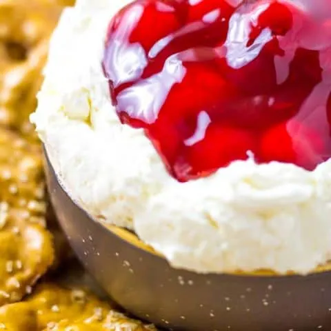 Extreme Close up of Cherry Pretzel salad dip in a dark gray bowl and a few pretzel thins