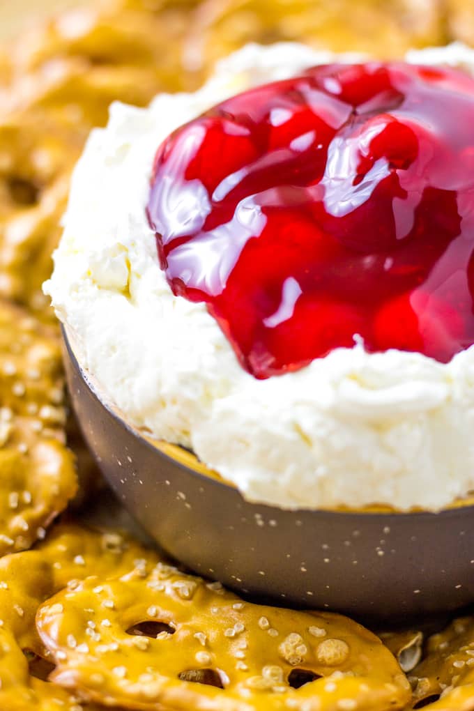 Extreme Close up of Cherry Pretzel salad dip in a dark gray bowl and a few pretzel thins