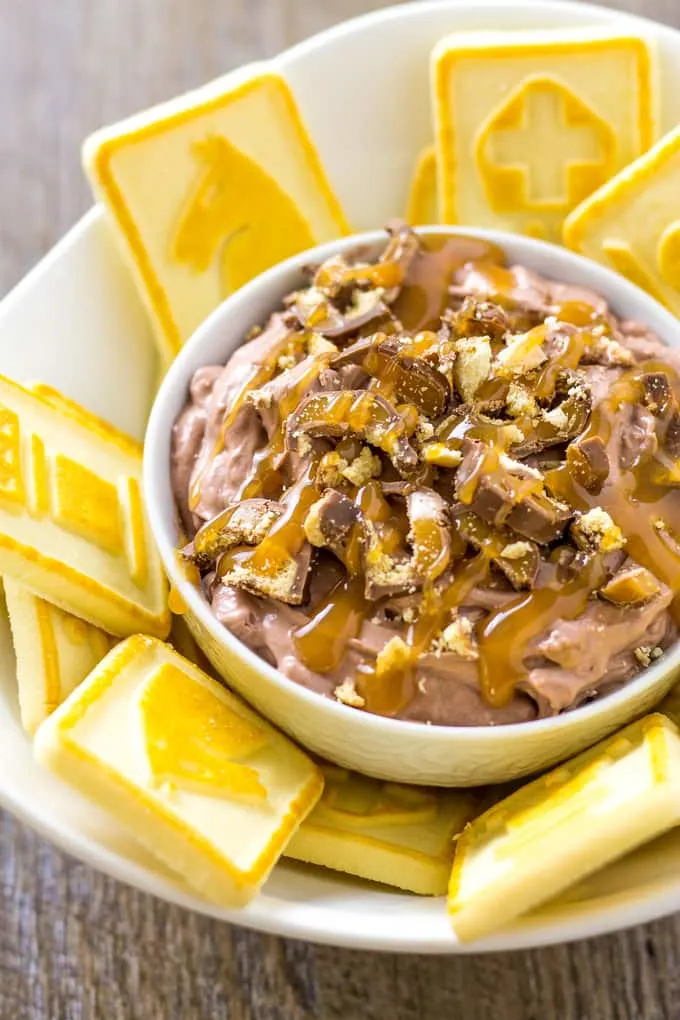 Chopped Twix candy bars on top of Twix dip in a bowl