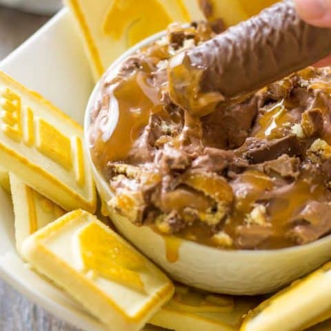 Dipping a twix candy bar in to the twix dip