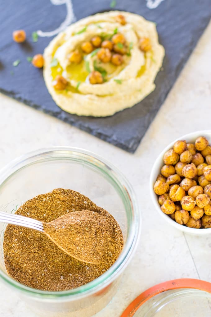 side view of shawarma seasoning in a jar next to chickpeas