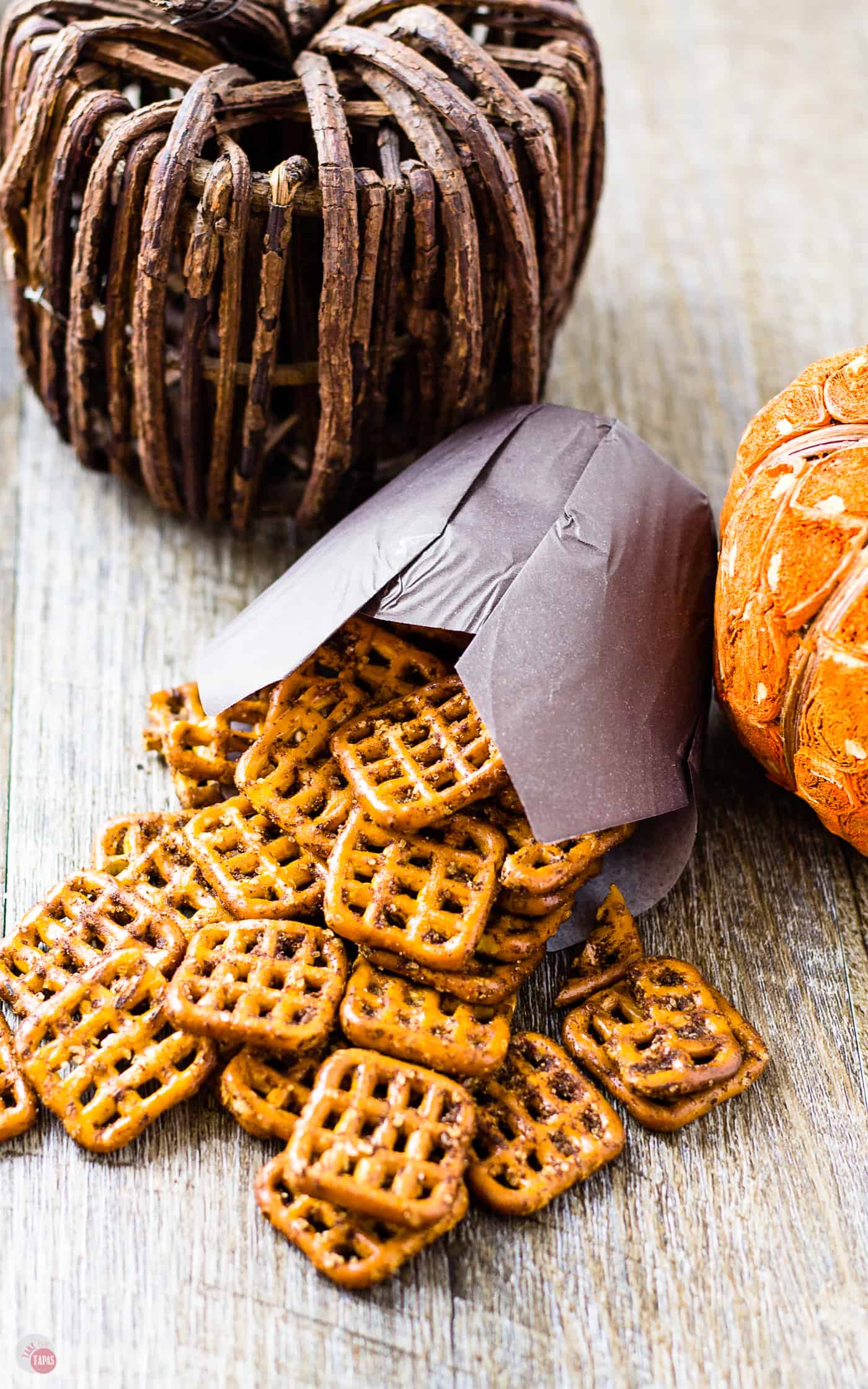 Pumpkin Spice Espresso Pretzels spilling out of a cupcake wrapper on to a wood table