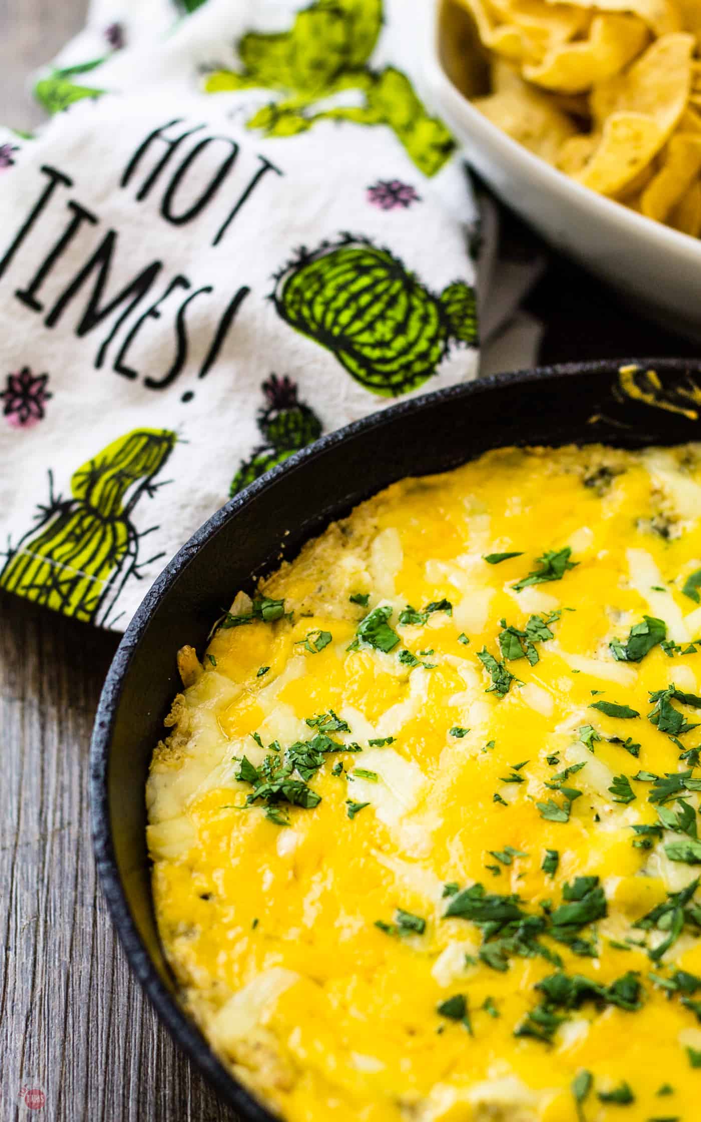 overhead picture of the chile relleno skillet dip, a hand towel and corn chips on a wooden table