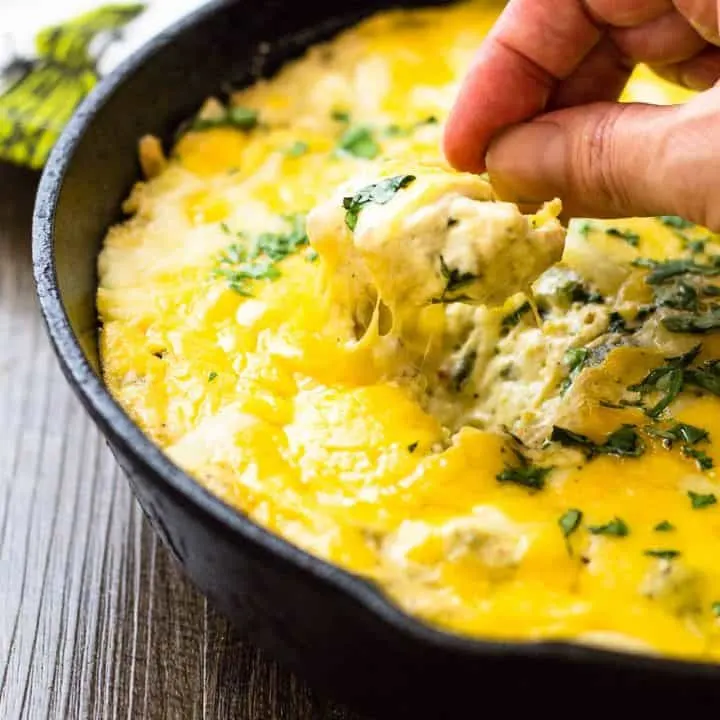 hand dipping a chip in to the chile relleno skillet dip