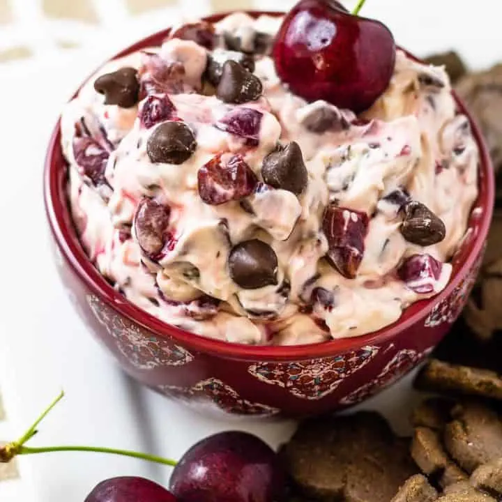 overhead picture of Drunken Cherry Garcia Dip in a red bowl sitting on a white plate with cherries and chocolate cookies