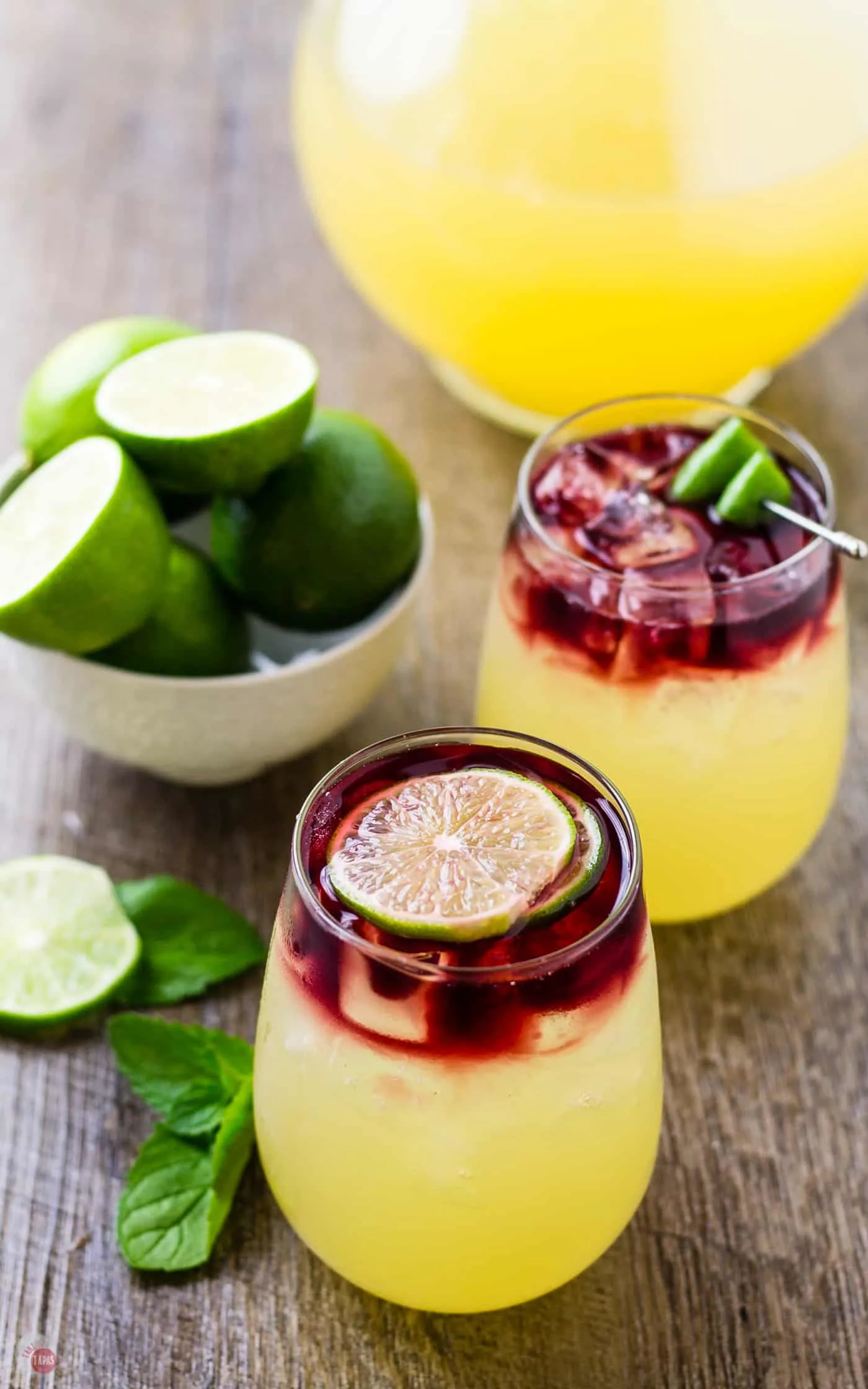 The layered look of the Wimade comes from the dark red wine or juice poured slowly on top of the limeade | Take Two Tapas | #Wimade #Wine #Limeade #HoneyLimeade #Wine #LayeredCocktail