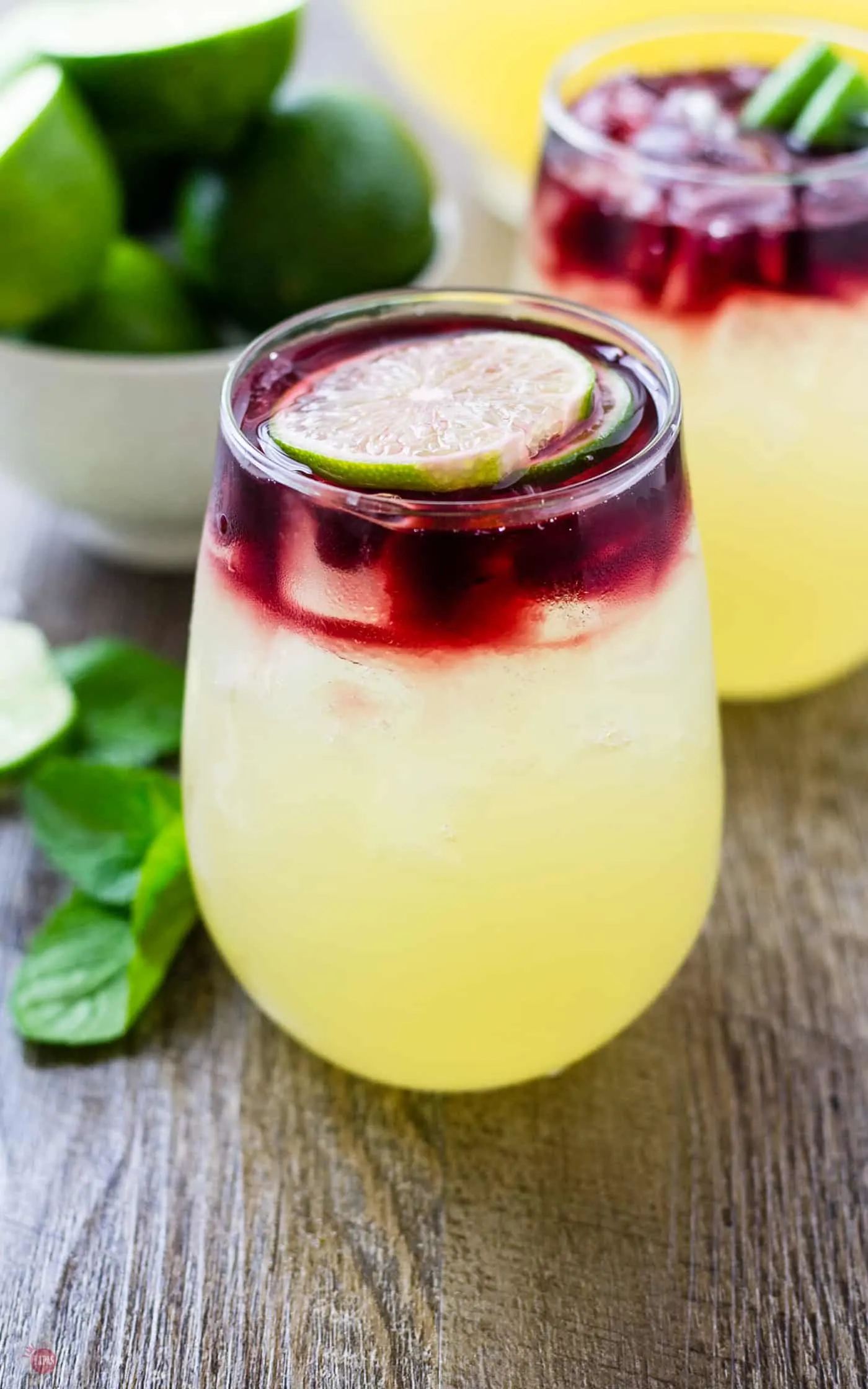 Get the stunning layered look of the Wimade by pouring your wine onto a slice of lime so it diffuses gently over the homemade honey limeade | Take Two Tapas | #Wimade #Wine #Limeade #HoneyLimeade #Wine #LayeredCocktail