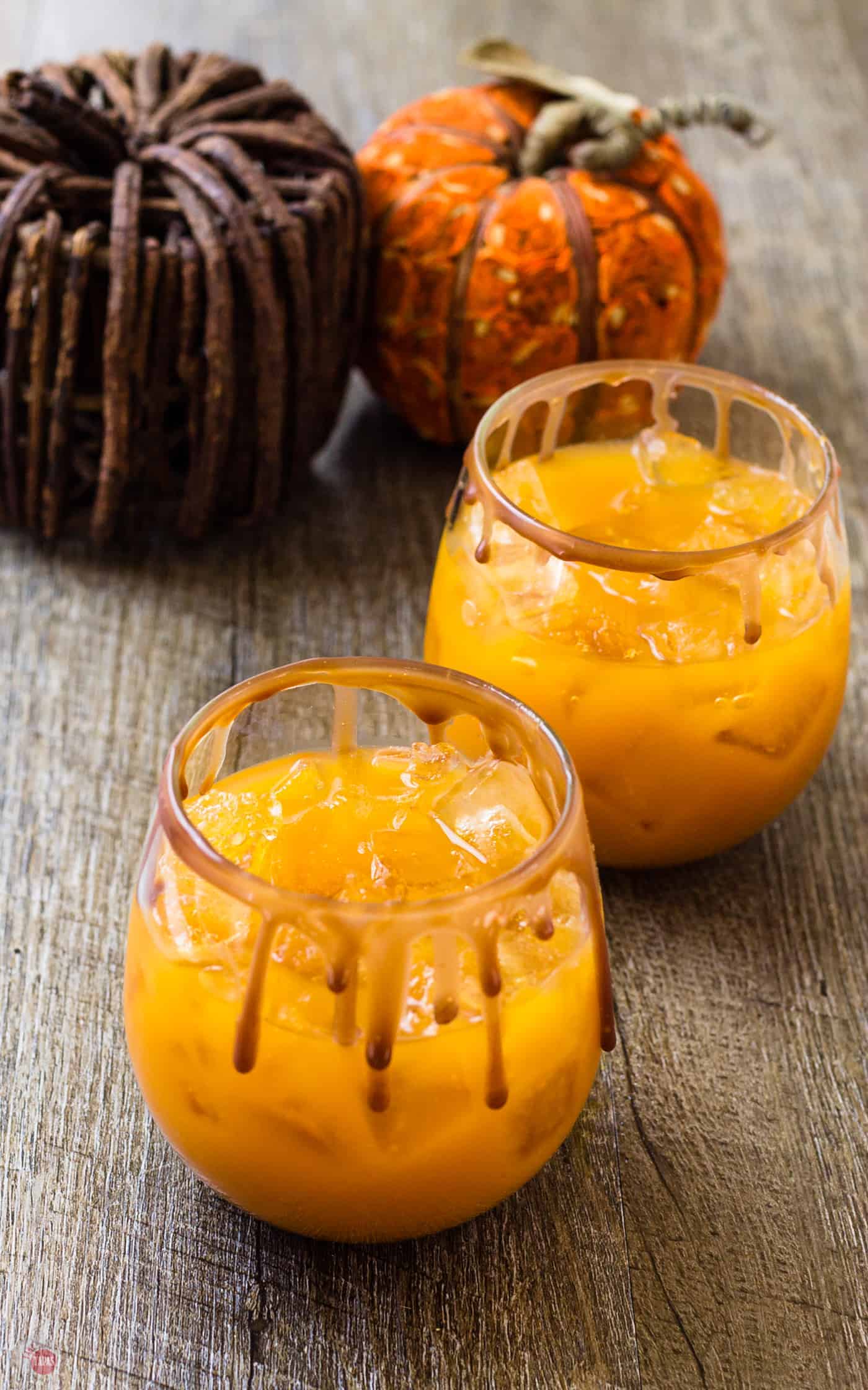 2 cocktails with the chocolate caramel sauce dripping on the glasses sitting on a table