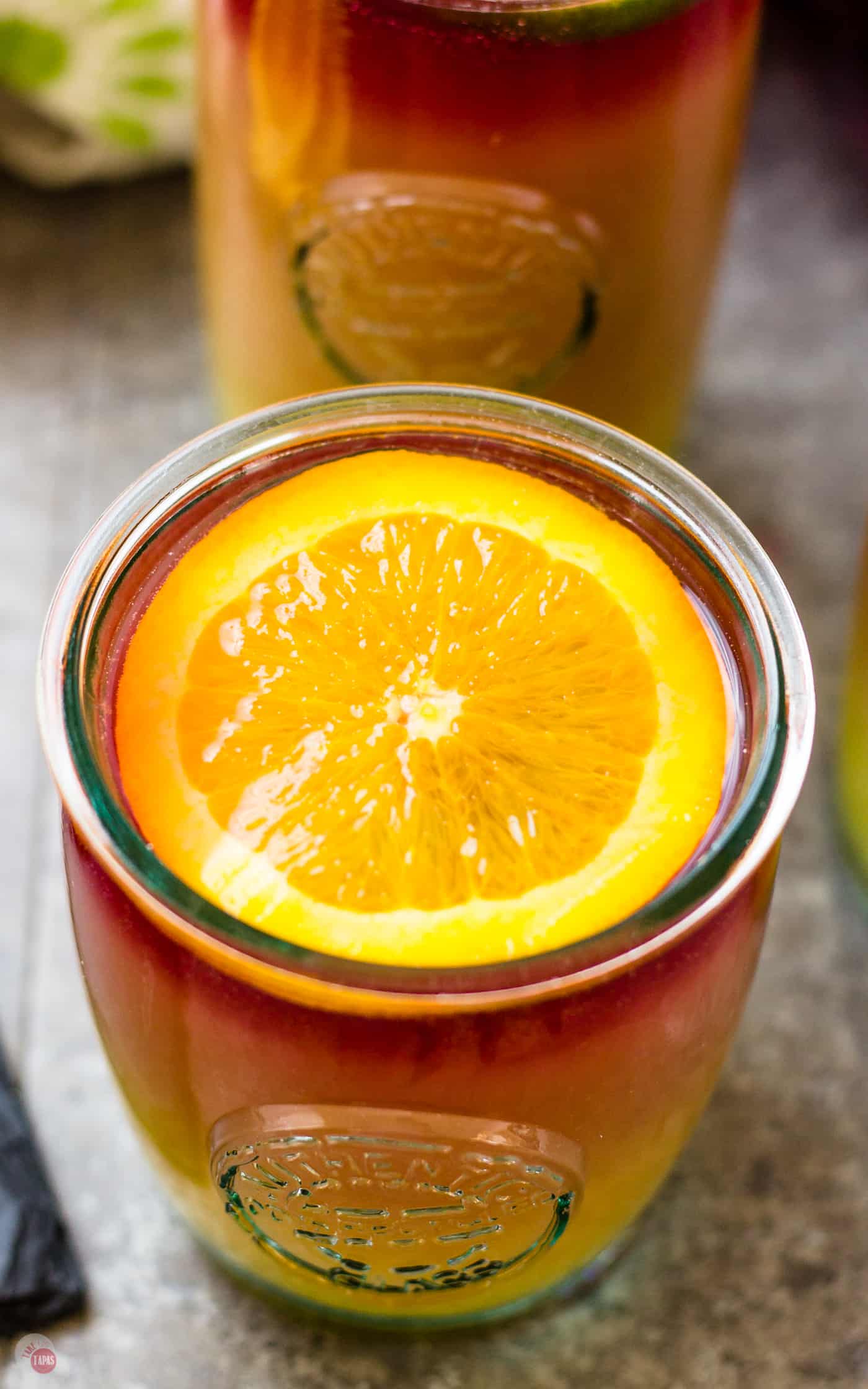 A slice of your favorite fruit is your tool for getting the layered look in your Sangria Sunrise | Take Two Tapas | #Sangria #TequilaSunrise #LayeredCocktail #OrangeJuice #TequilaCocktails #BrunchCocktails