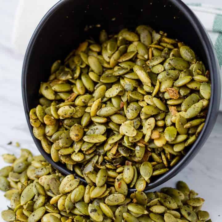 Crunchy Southwest Pepitas spilling out of a bowl on to a table