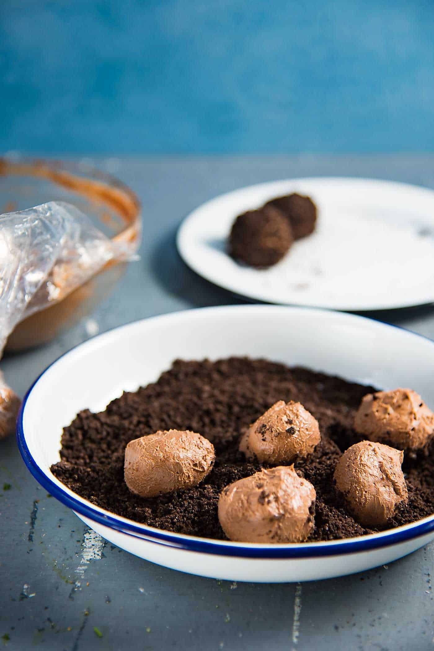 No bake cheesecake bites being rolled in Oreo cookie crumbles