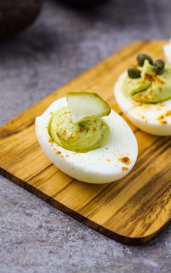 avocado deviled eggs with pickle on top