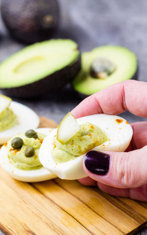 Hand holding an avocado deviled egg