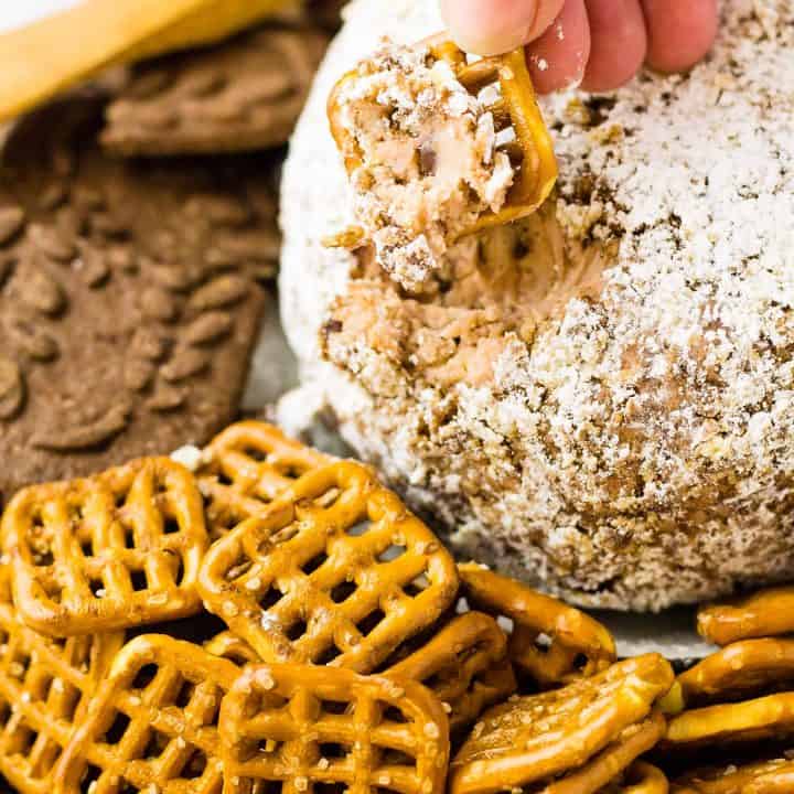 Hand with a recently dipped Salted pretzel and the cheese ball