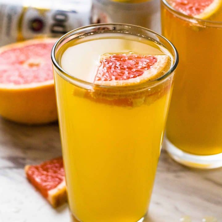 side view of Grapefruit Shandy on a white and black surface