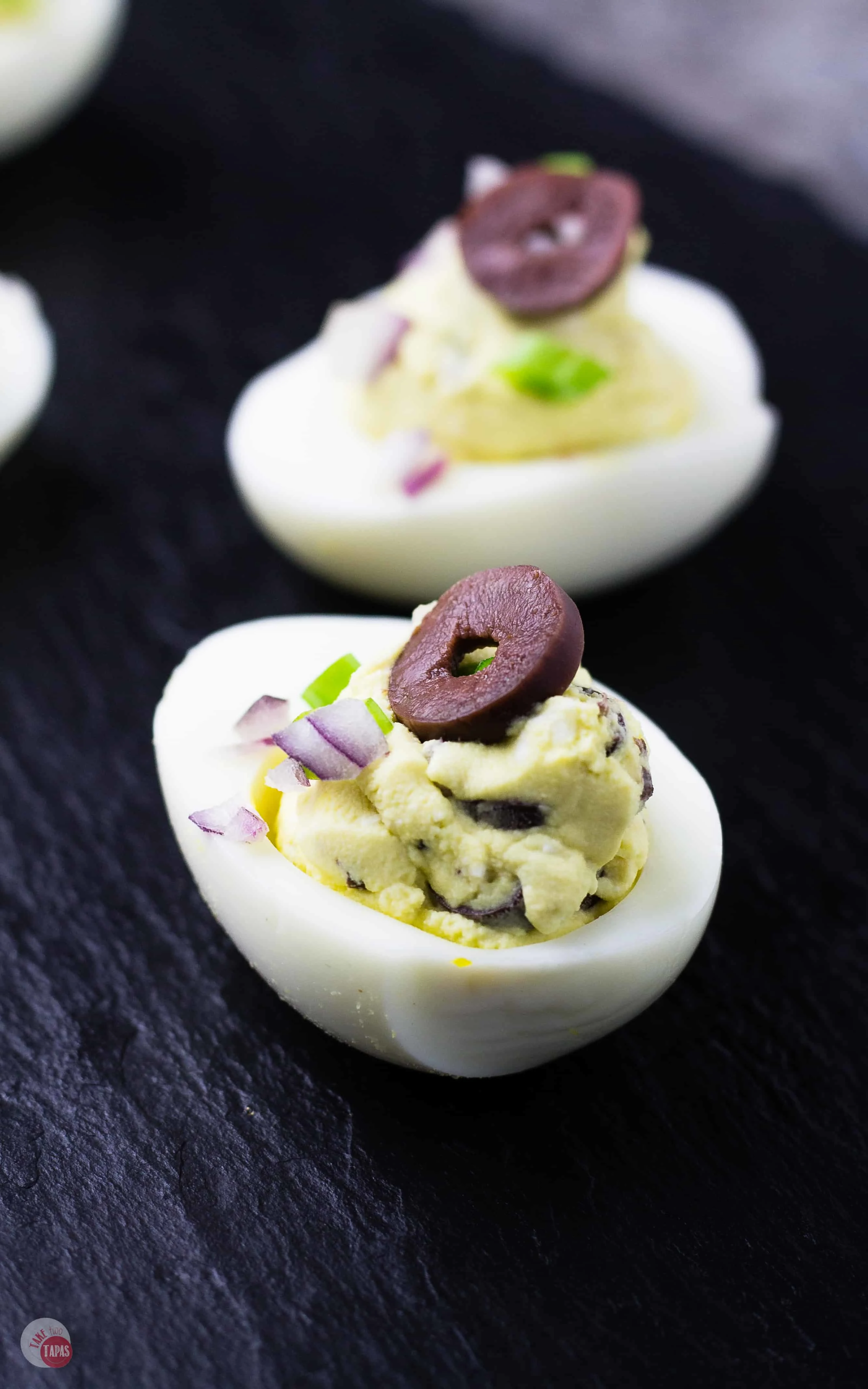 row of mediterranean deviled eggs on slate tray