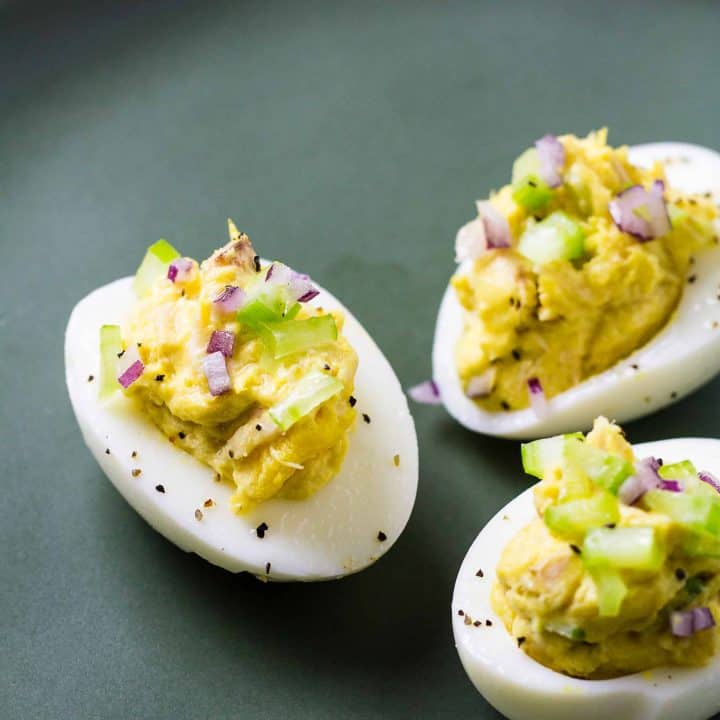 three deviled eggs with tuna salad on a plate