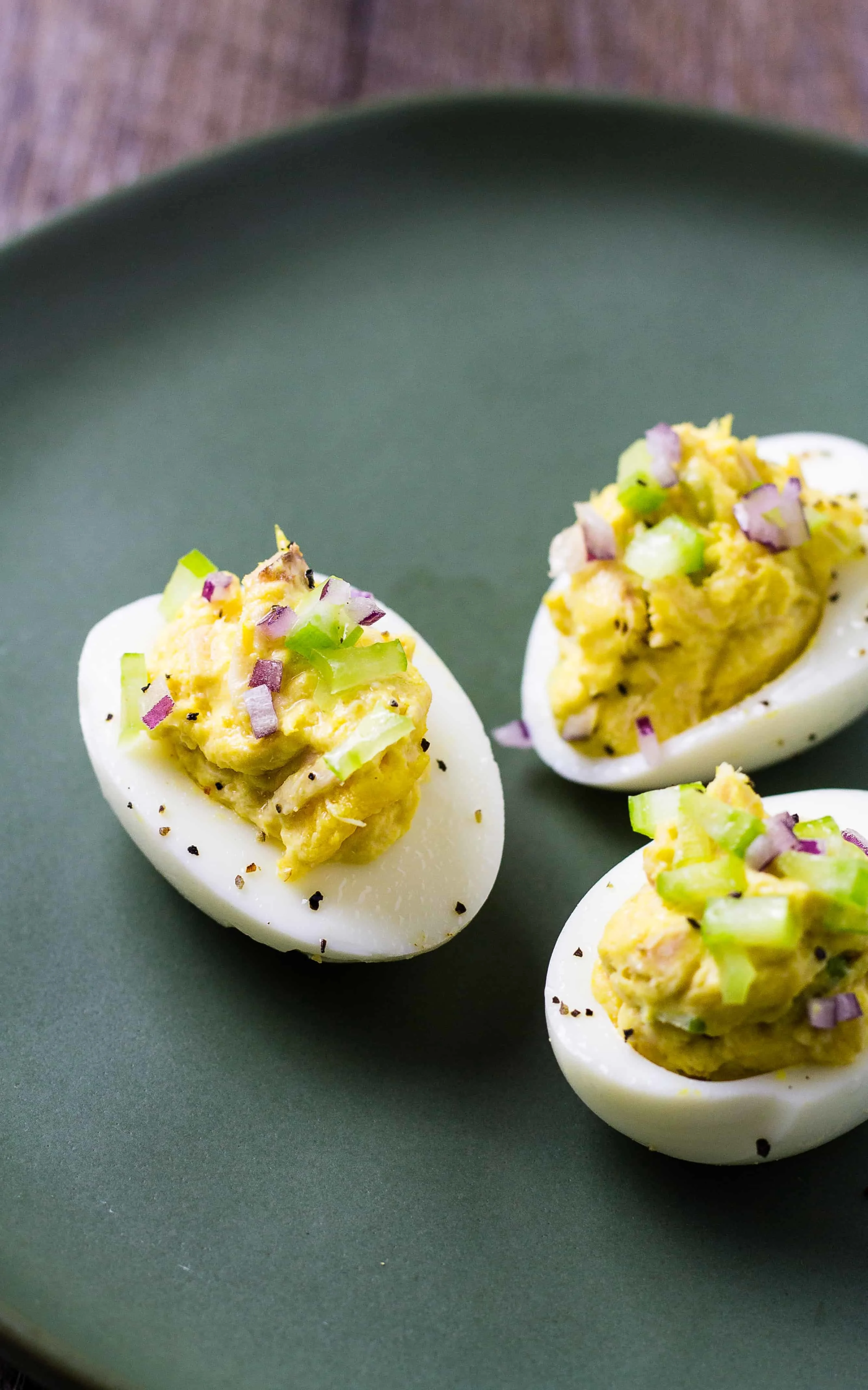 three deviled eggs with tuna salad on a plate