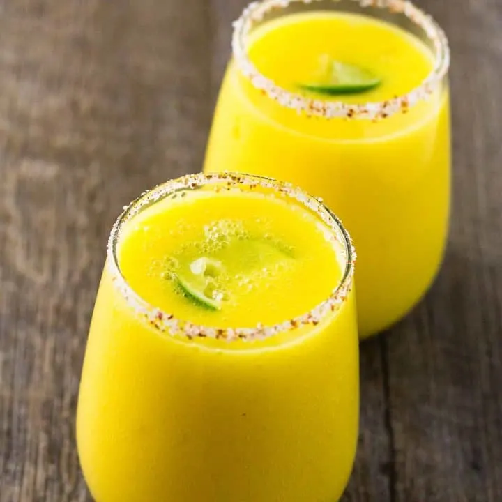 2 Spicy Mango Margarita with a Spicy Tajín Salt rim on a table