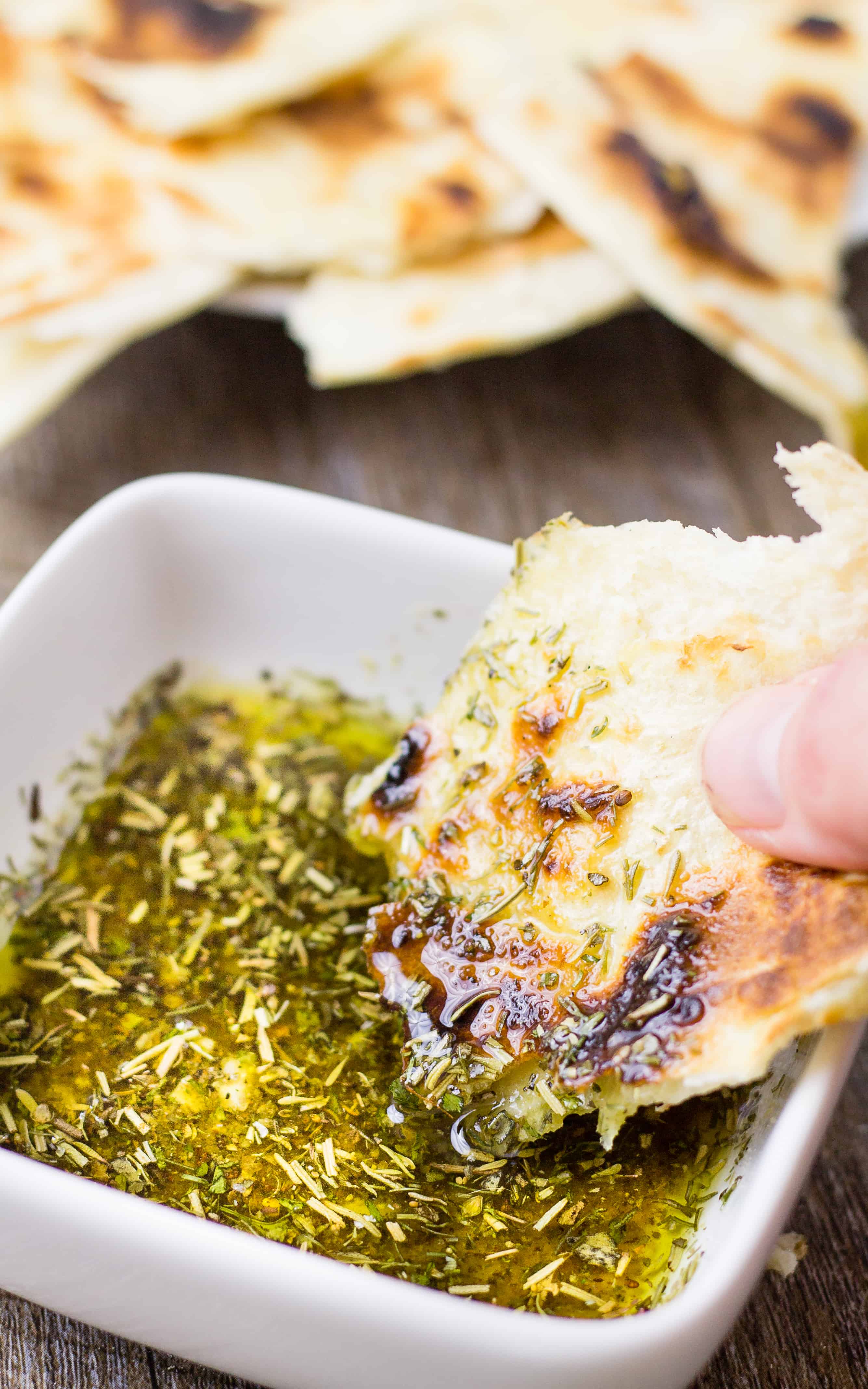 Close up of hand dipping pita bread in to the Greek Dipping Oil