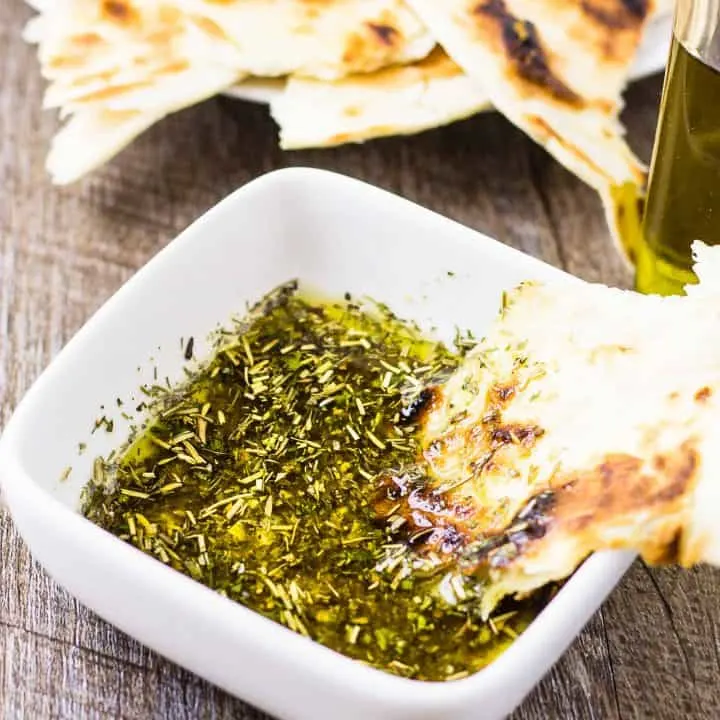 Greek Dipping Oil in a white bowl with Pita on a wood table