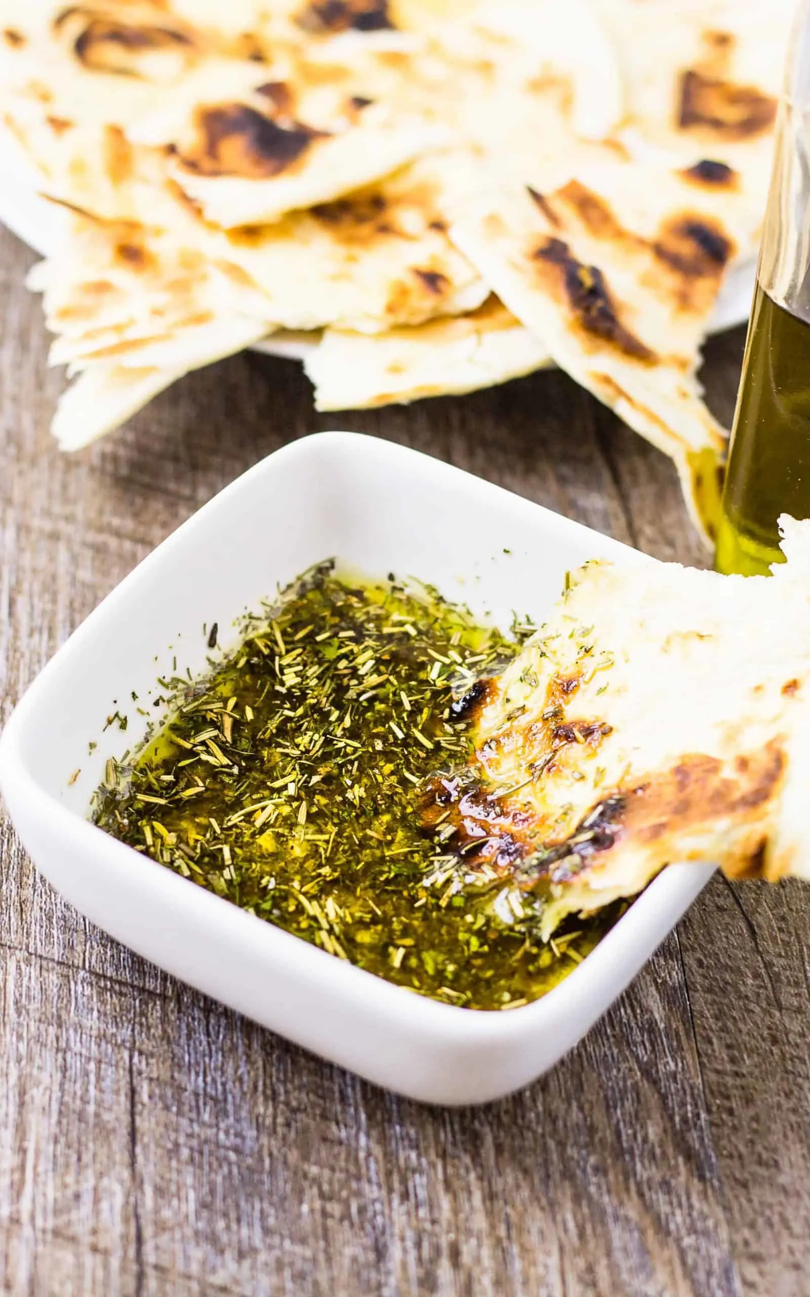 Greek Dipping Oil in a white bowl with Pita on a wood table
