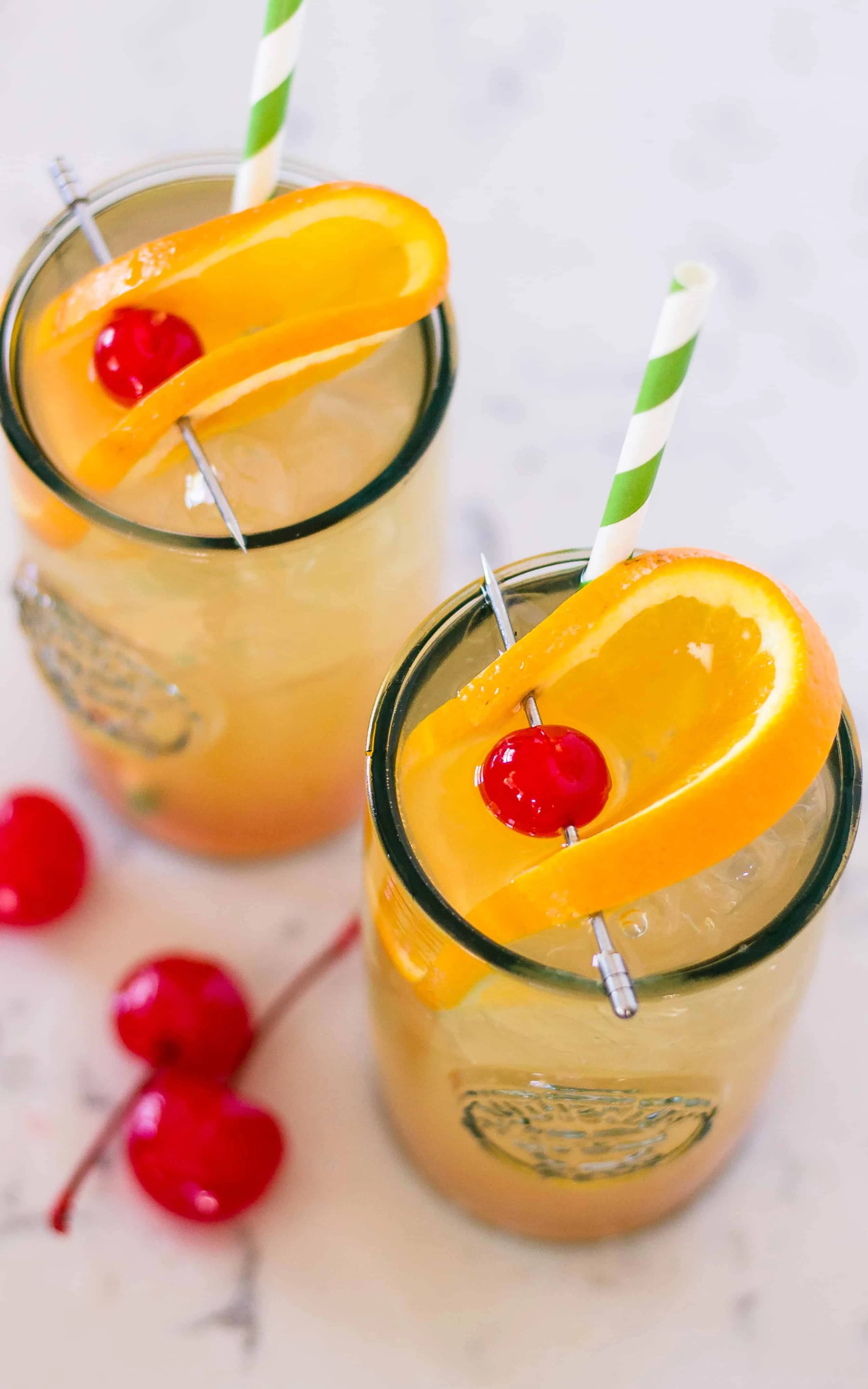 two cocktails with orange garnish