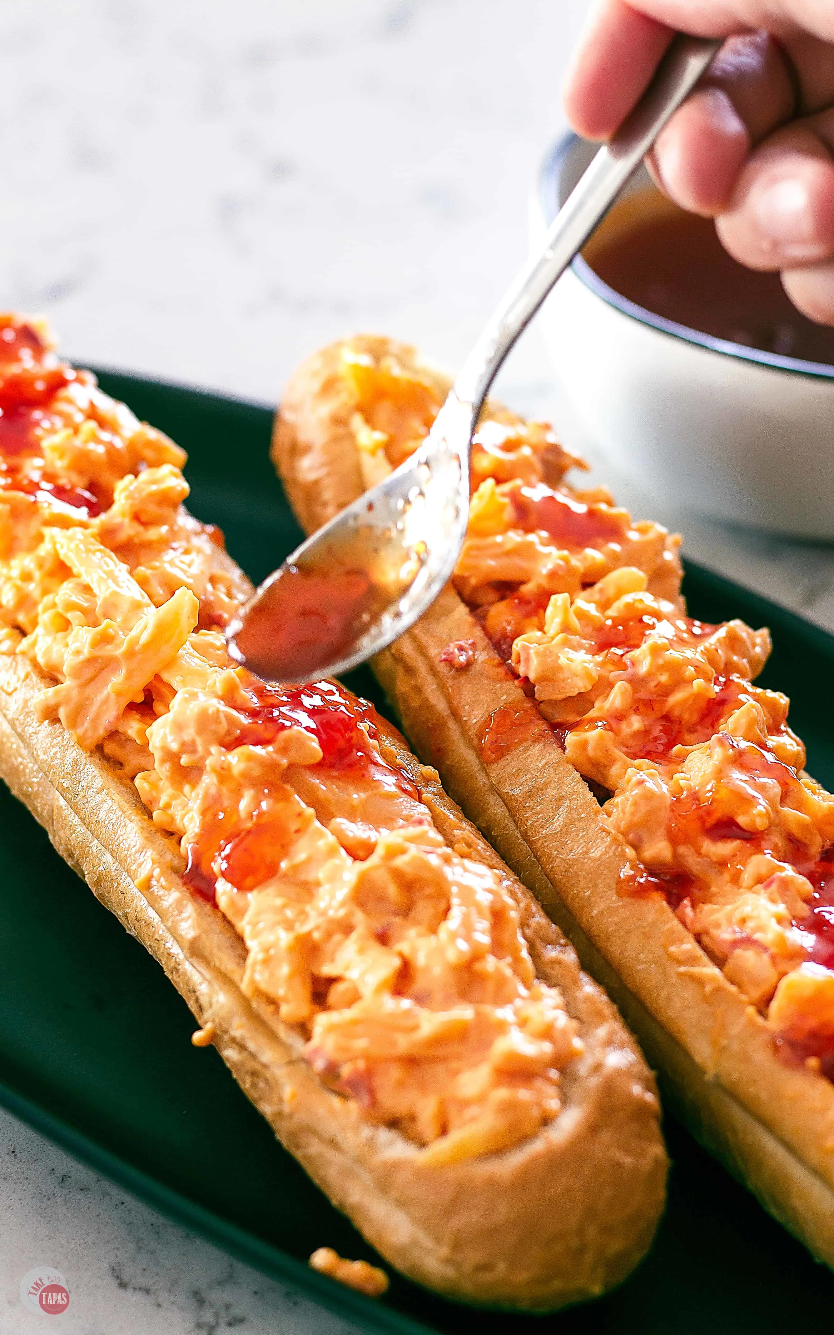 spooning pepper jelly on the pimento cheese stuffed bread