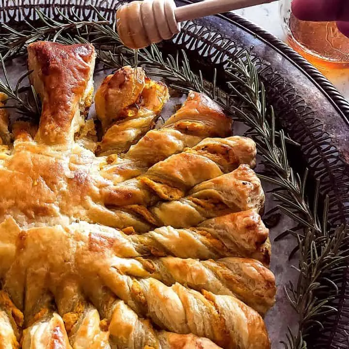 Honey being drizzled on Easy Golden Brown and Flaky Pumpkin Pull Apart Puff Pastry