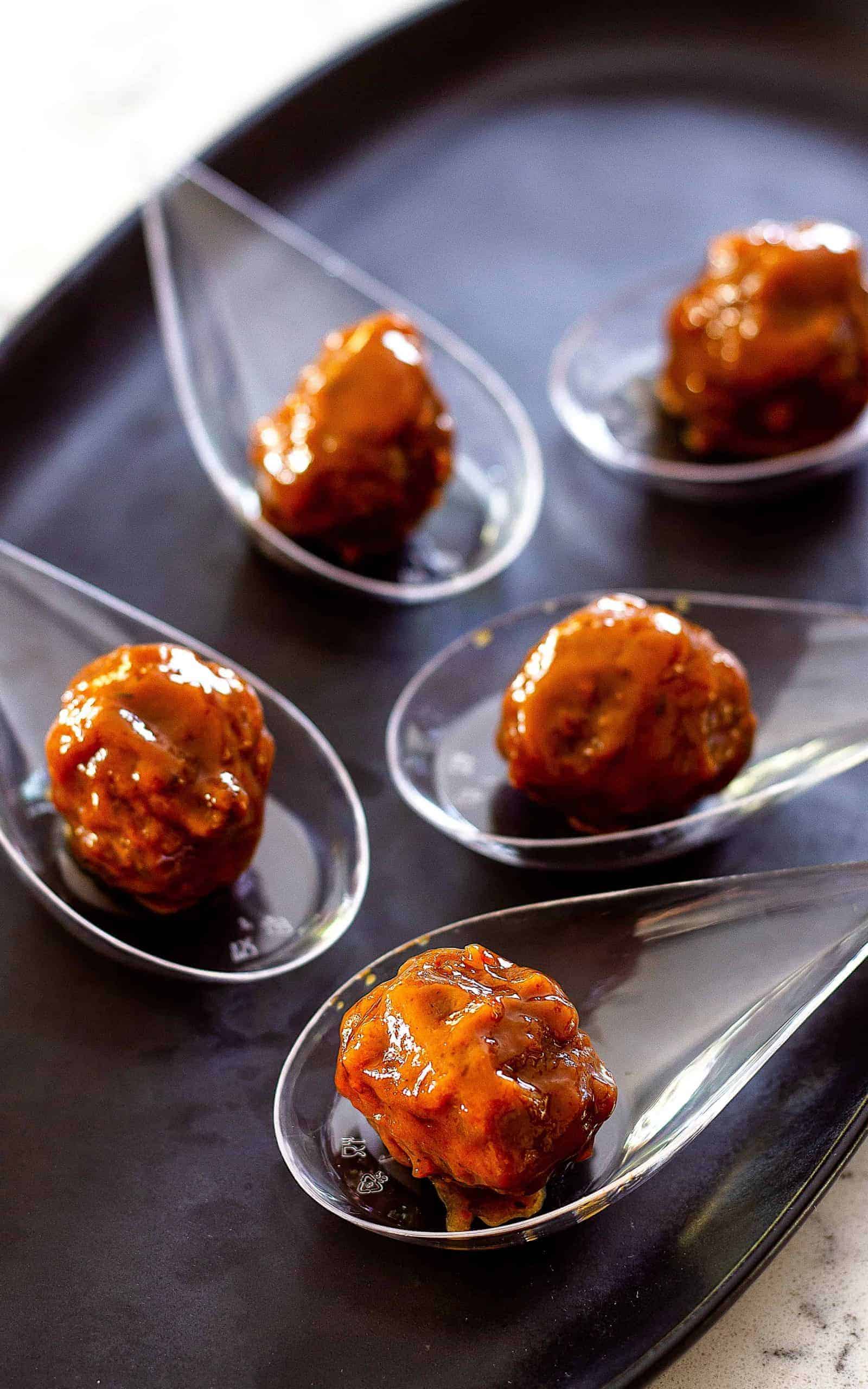 party meatballs in clear spoons on a platter