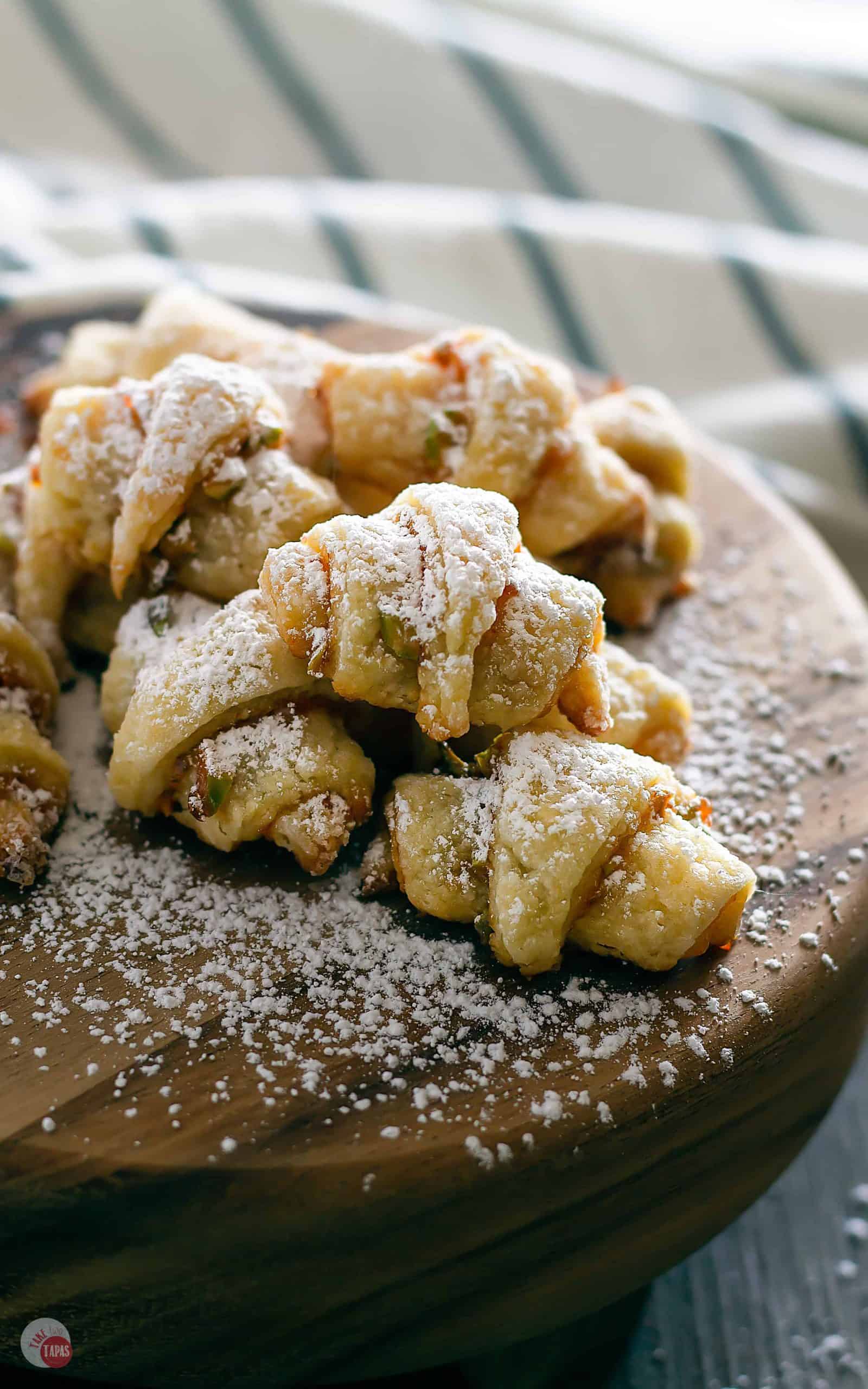 Rugelach on wooden platter covered in powdered sugar