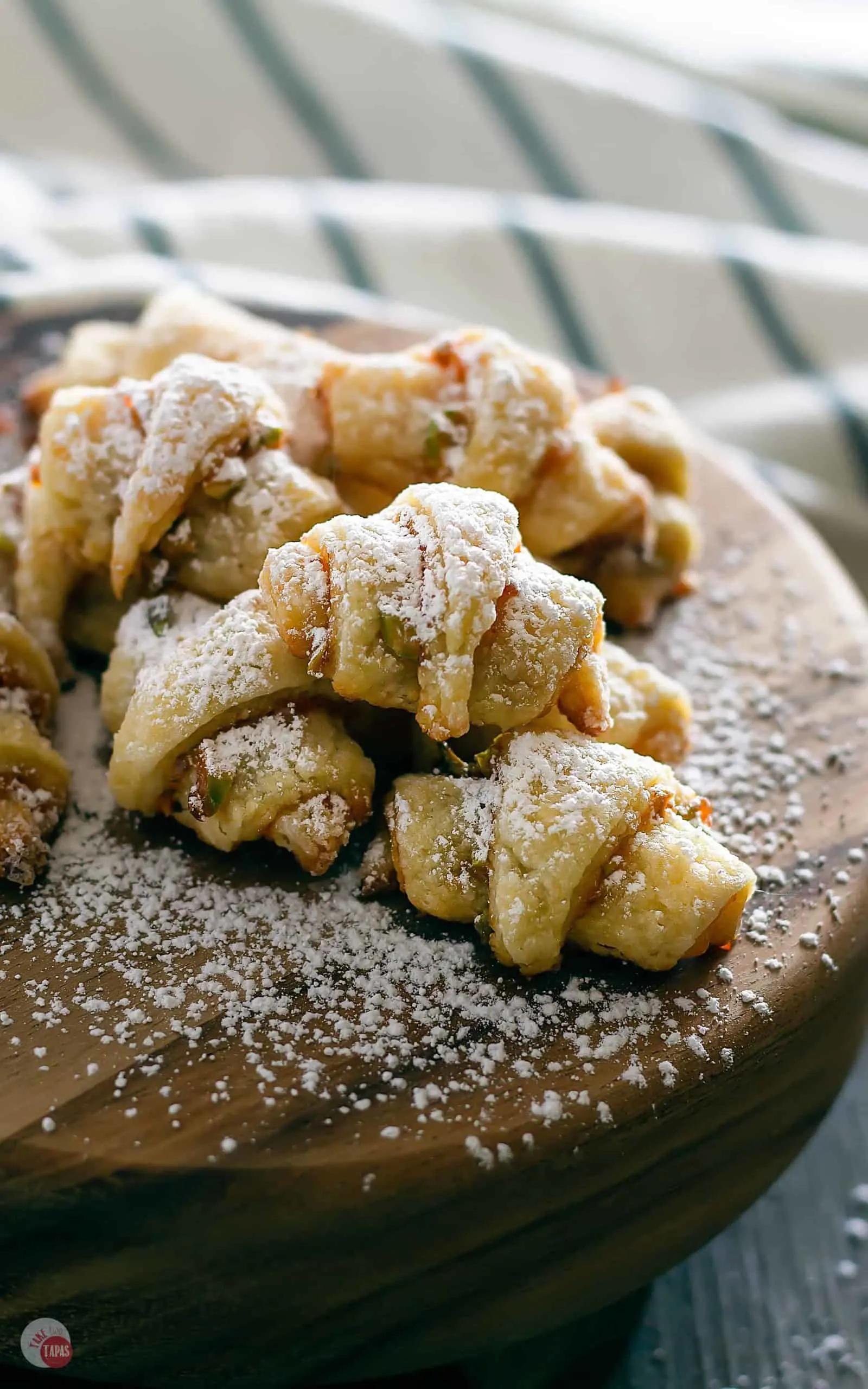 Rugelach on wooden platter covered in powdered sugar