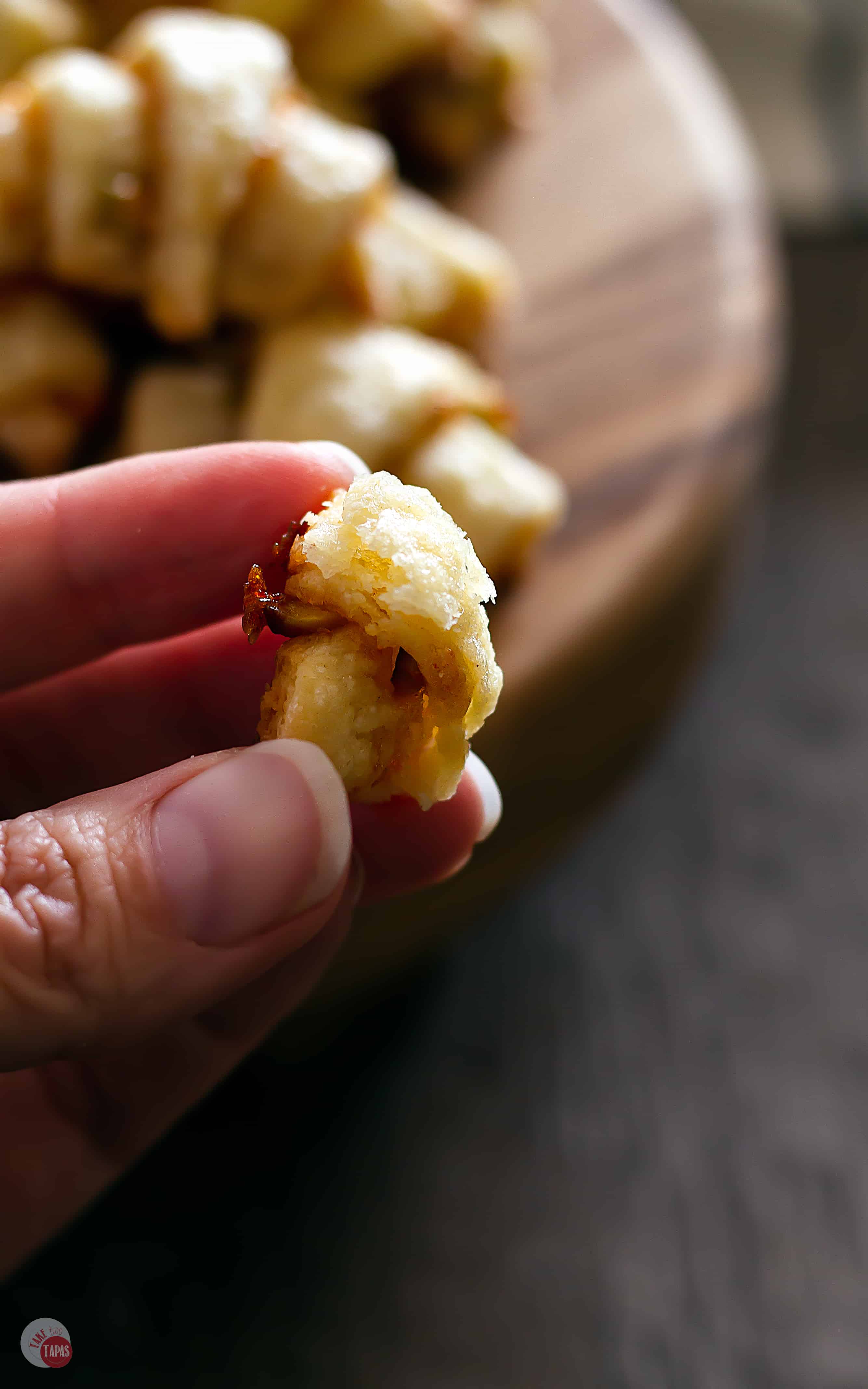 hand holding piece of rugelach with others in background on platter