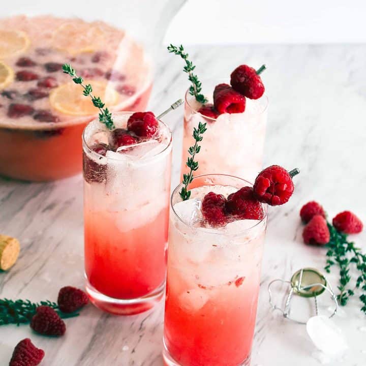 Three glasses of Raspberry Thyme Prosecco Punch on a table
