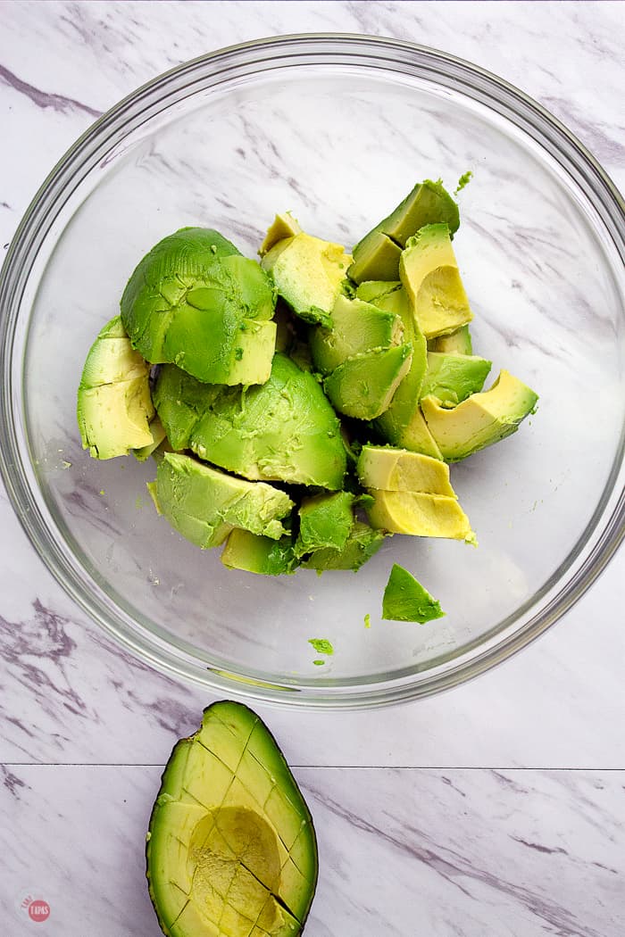 Score the avocado flesh with a knife before scooping out into a bowl for easier mashing. | Take Two Tapas | #Guacamole #Pomegranate #SavorWinningFlavors #AvocadosFromMexico #HAVEARITA #FlavorYourWorld