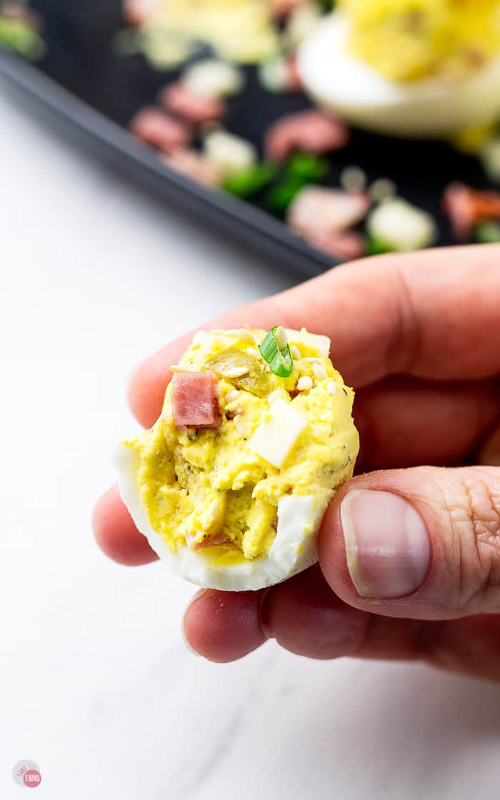 hand holding a muffuletta egg with a bite missing