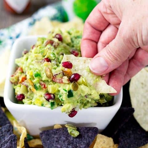 A person is dipping a chip in to the guacamole