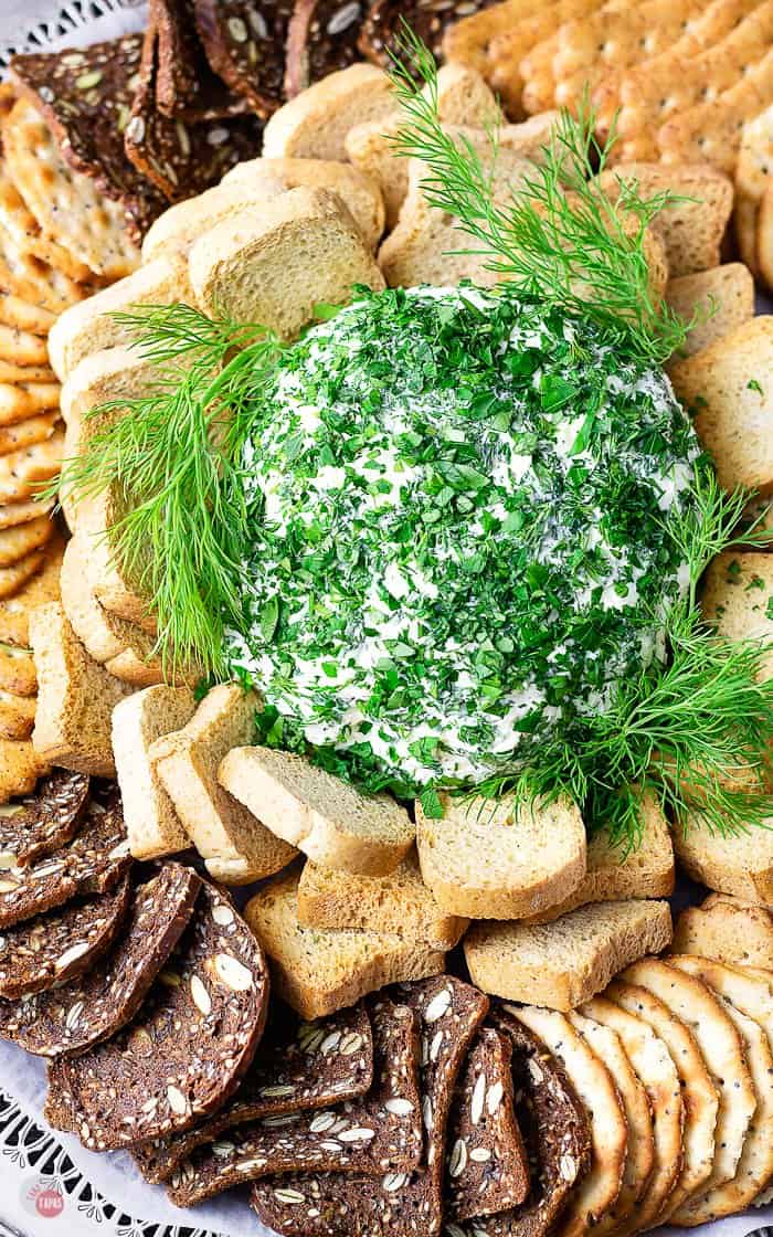 cheese ball covered with herbs surrounded with crackers