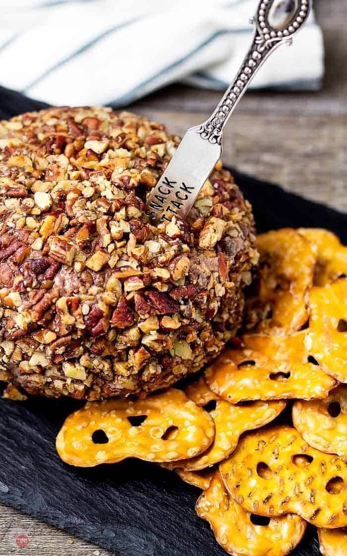 side view of derby pie cheese ball covered in toasted pecans on slate platter