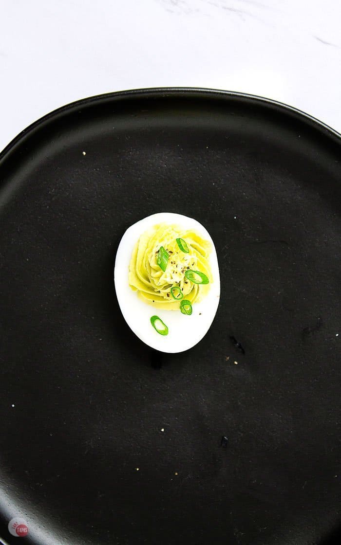 overhead shot of deviled egg on black plate