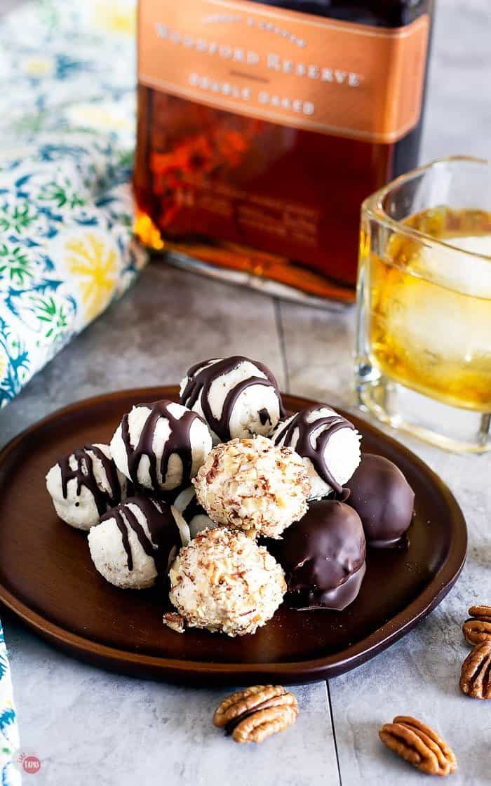Derby Week Bourbon Balls on a wood serving dish with Bourbon Neat on a table