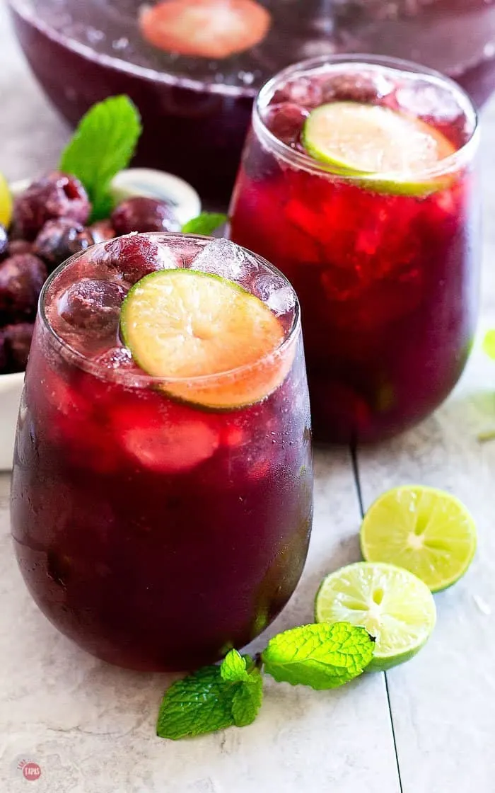 close up of cherry cream soda punch in wine glasses with frozen cherries and lime slices