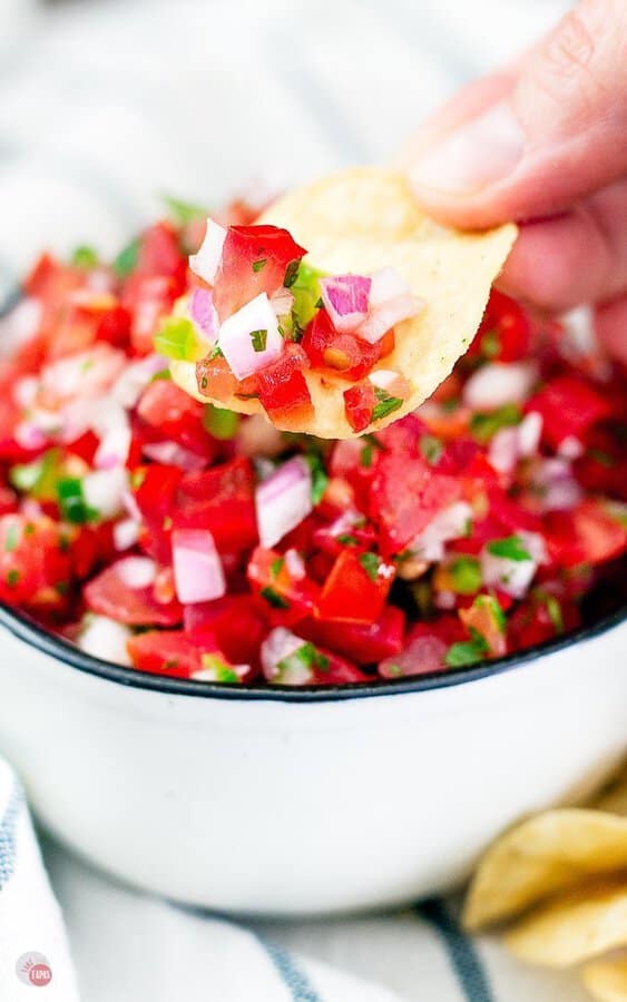 pico de gallo being scooped with a chip